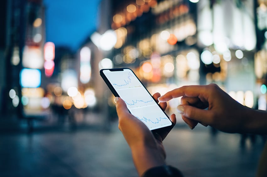 Person mit Telefon in der Hand vor nächtlicher Straßenszene in der Stadt