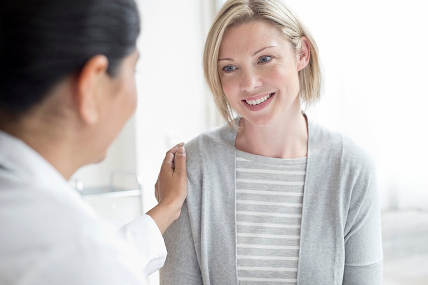 Ärztin mit Hand auf der Schulter der Patientin.