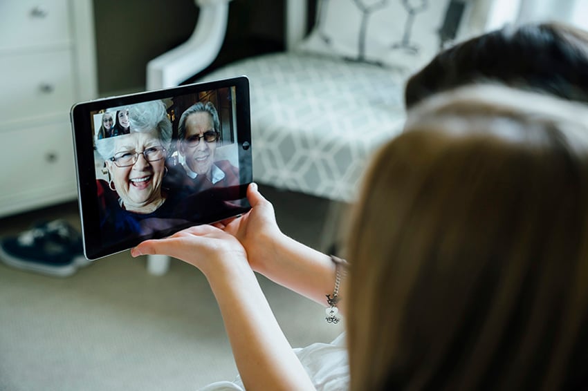 Sisters video conferencing with grandparents through tablet computer at home